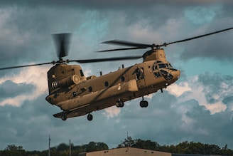 a large military helicopter flying through a cloudy sky