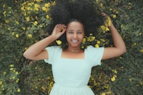 A smiling woman comfortably lounging in stylish innerwear, surrounded by fresh flowers.