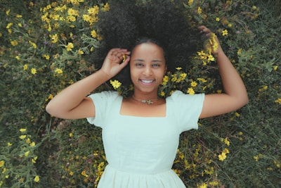 A smiling woman comfortably lounging in stylish innerwear, surrounded by fresh flowers.