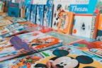 An assortment of colorful children's books arranged on a surface. The books feature popular animated characters and themes, with prominent illustrations on their covers.