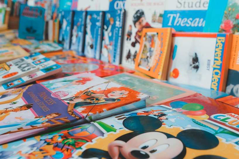 An assortment of colorful children's books arranged on a surface. The books feature popular animated characters and themes, with prominent illustrations on their covers.