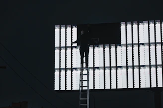Technician adjusting a large LED billboard on a rooftop overlooking the cityscape of Calama.