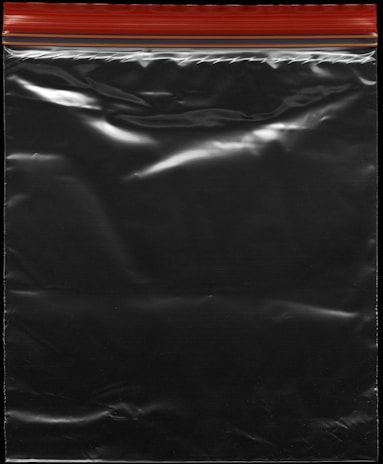 A transparent plastic zipper storage bag with a red and yellow sealing stripe at the top. The bag appears shiny under light, showing reflections and creases in the material.