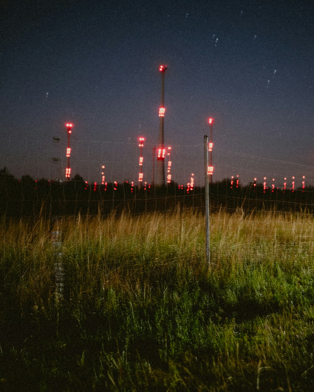 a field with a fence and a bunch of red lights