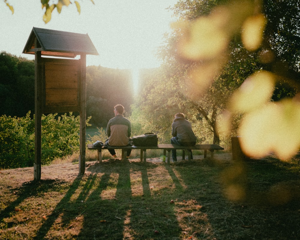 a couple of people sitting on top of a wooden bench