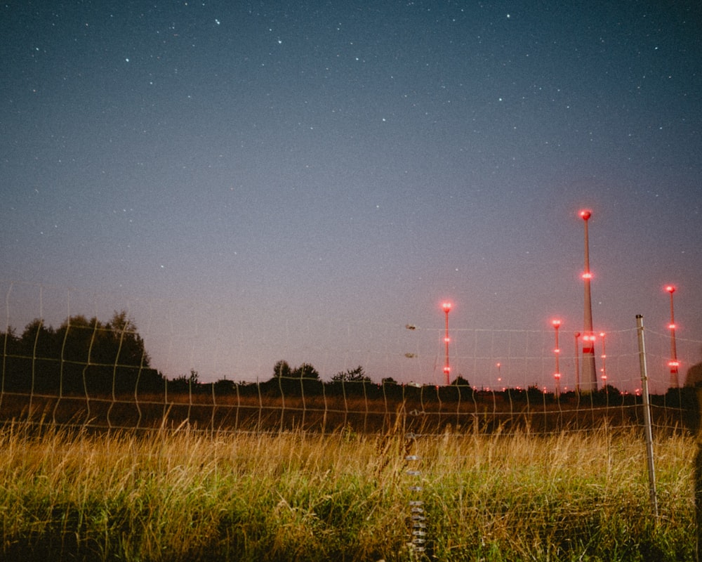a field with a fence and some red lights