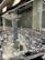 A detailed architectural model of a city, featuring numerous high-rise buildings, roads, and infrastructure. The centerpiece is a tall, prominent skyscraper surrounded by other modern structures. The setting seems to be a showroom or exhibition area with reflective surfaces and ceiling lights.