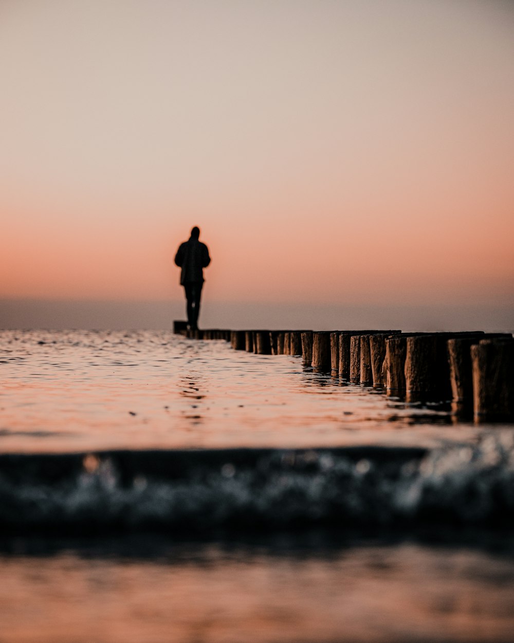 a person standing on a pier looking out at the ocean