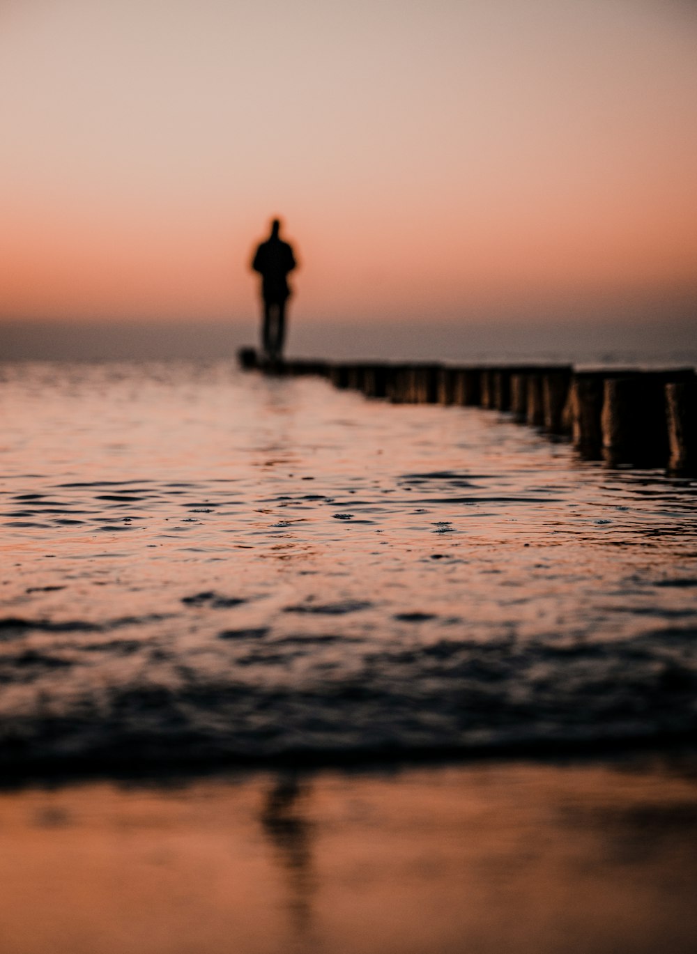 a man standing on a pier looking out at the ocean