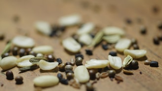 A close-up of moringa leaves and seeds arranged on a wooden table.