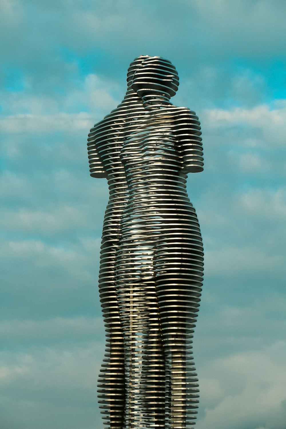 a statue of a woman standing in front of a cloudy sky
