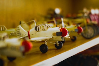 Close-up of a detailed model airplane collection displayed on a wooden shelf with Munich Airport posters in the background.