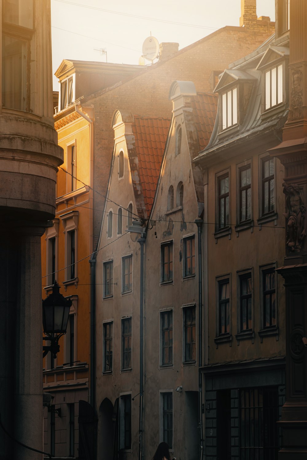 a woman walking down a street past tall buildings