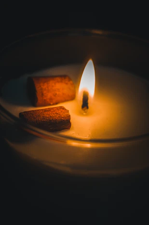 Close-up of a cinnamon and clove scented candle with a golden flame flickering.