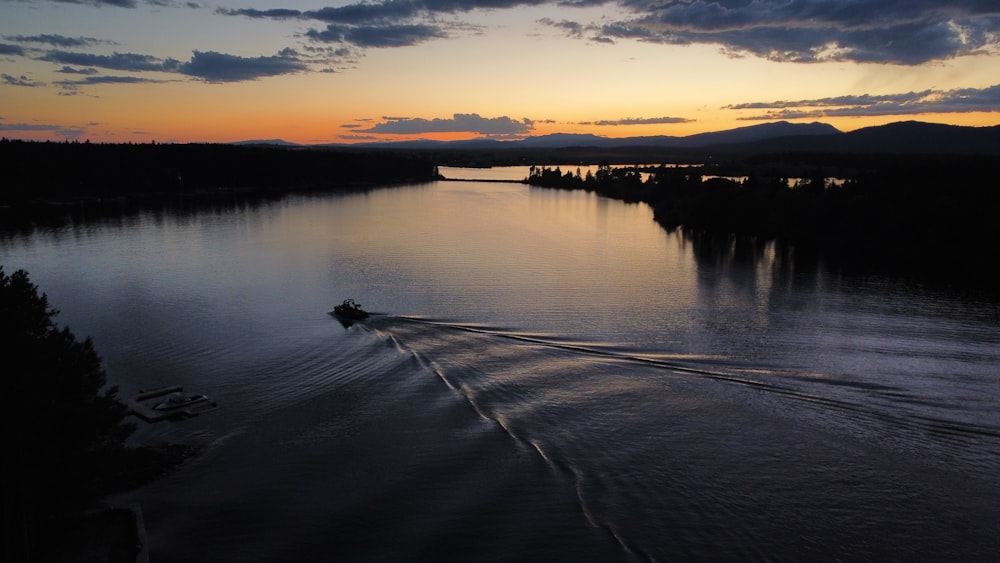 a boat traveling down a river at sunset