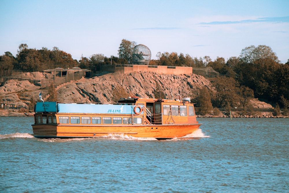 a boat traveling down a river next to a hill