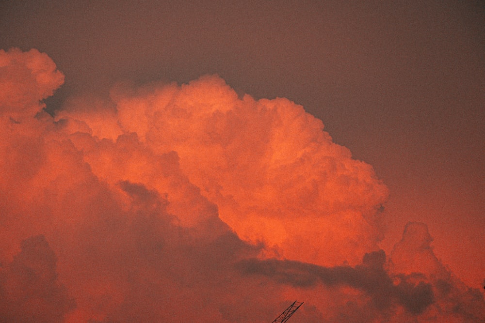 a plane flying through a cloudy sky at sunset