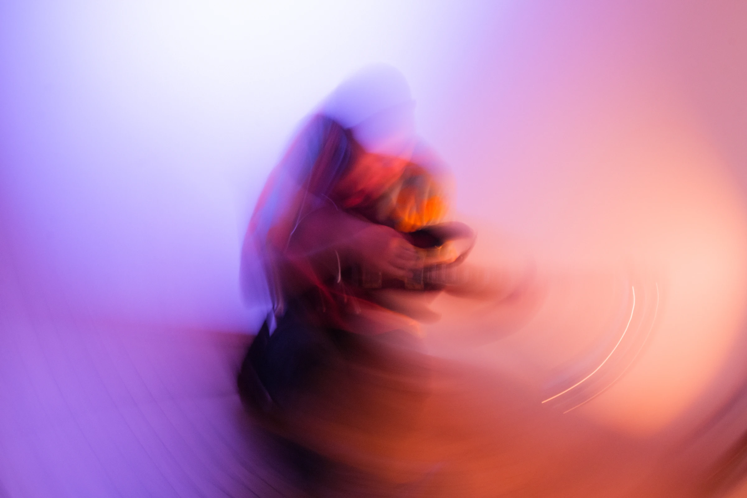 A blurred figure holding a phone in violet light