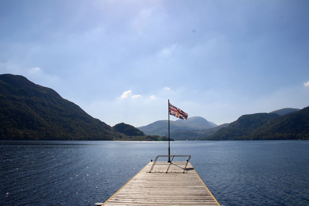a boat dock with a flag on it and mountains in the background
