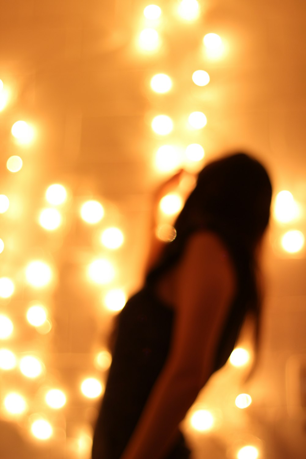 a blurry photo of a woman standing in front of a wall of lights