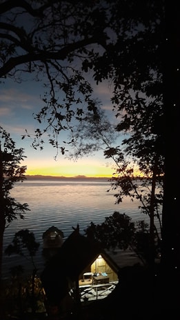 Sunset view over the calm river beside cozy wooden cottages at Haven by the Lake.