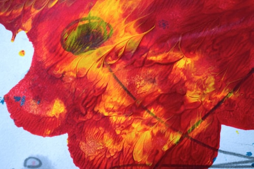 Abstract art featuring vibrant, swirling patterns of red, orange, and yellow with hints of green and blue. The design creates dynamic movement and resembles flowing textures, possibly resembling a fiery scene or a bright autumn leaf.