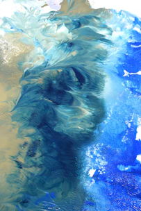 Abstract acrylic painting with swirling blues and greens creating a sense of movement.