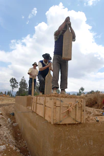 Workers applying natural soil compaction techniques on a garden pathway under sunlight.