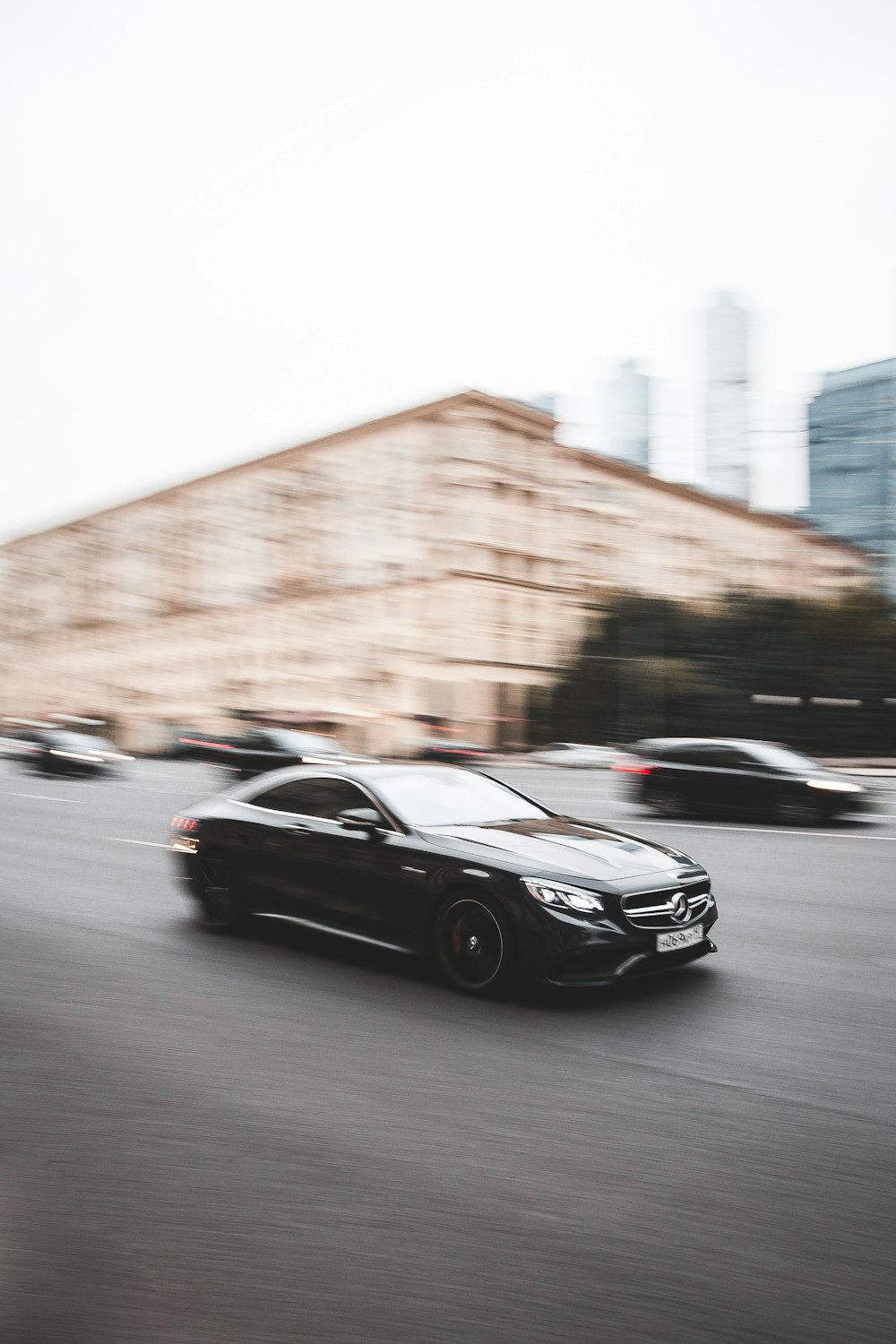 a black car driving down a street next to tall buildings