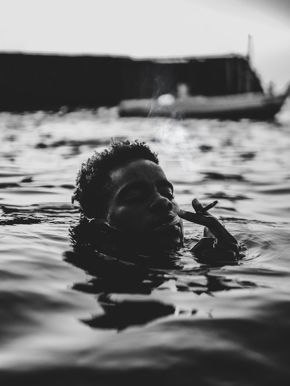 a man floating in the water with a cigarette in his mouth