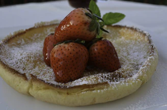 Small child smiling as they enjoy a fluffy pancake topped with fresh fruit at the kitchen table