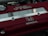 A close-up view of a car engine cover featuring the red and silver branding of a Honda DOHC VTEC engine. The cover has a metallic Honda logo and several screws visible.