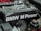 A detailed view of a BMW engine component featuring carbon fiber material with the text 'BMW M Power' prominently displayed. Various engine parts and components are visible around the main object, including cables, hoses, and connectors.