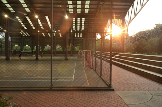 a tennis court with a sun setting behind it