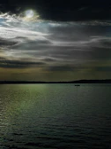 A ghostly sailboat drifting under a moonlit sky, shrouded in mist.