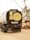 A truck with a tank displaying cartoon artwork on the back. The illustration features a large yellow face making a cheeky expression with one finger raised, situated against the backdrop of boats and industrial equipment.