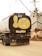 A truck with a tank displaying cartoon artwork on the back. The illustration features a large yellow face making a cheeky expression with one finger raised, situated against the backdrop of boats and industrial equipment.