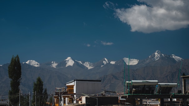 A solar panel installation on a rooftop with the Himalayan mountains in the background under clear blue sky.