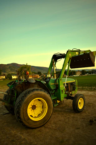 A happy farmer standing beside a Fotrak China tractor, smiling with his thumbs up in a green farm landscape.