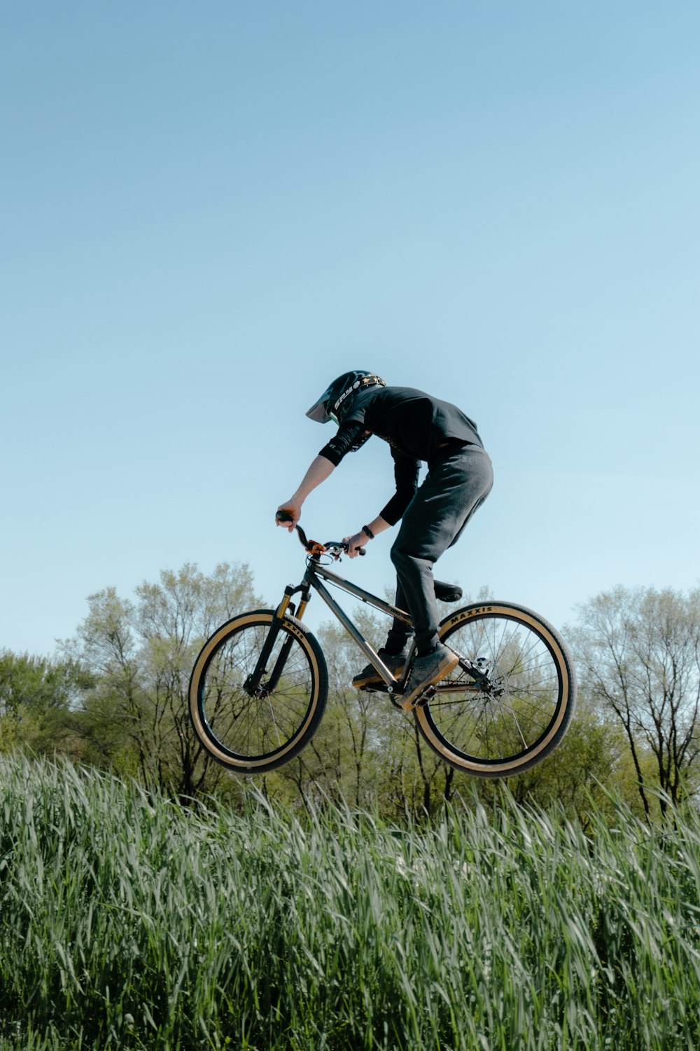 a man riding a bike over a lush green field