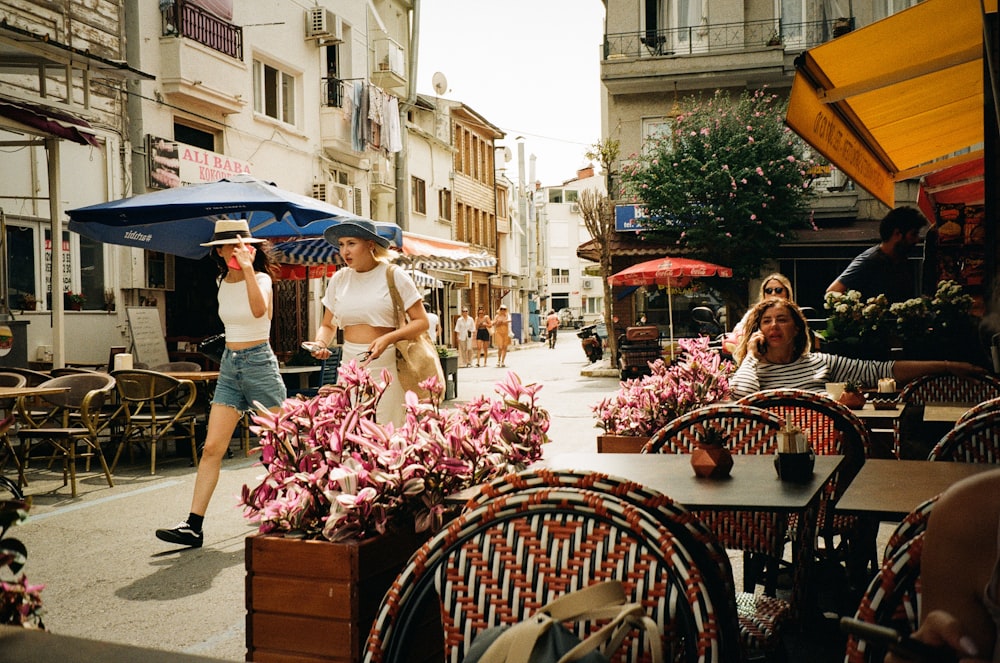 un groupe de personnes marchant dans une rue à côté de tables et de chaises