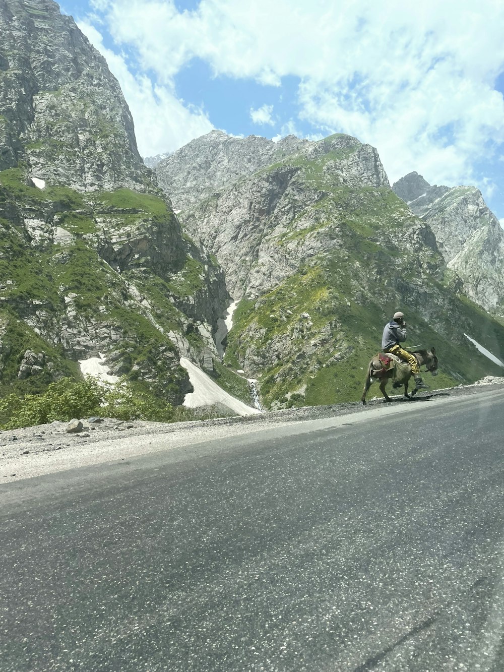 a man riding a horse down a mountain road