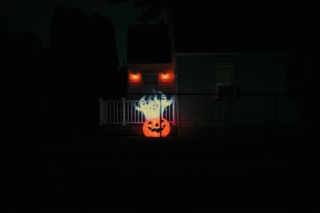 A warmly lit haunted garage entrance with friendly ghost decorations and families smiling nearby.