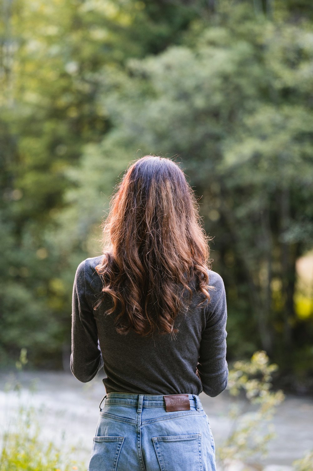 a woman with long hair standing in front of a river