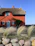 Cozy seaside cottage with blooming flowers in the garden under a bright blue sky.