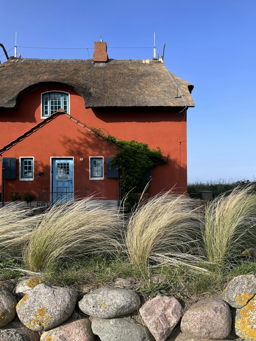 a red house with a thatched roof and a stone wall