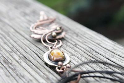 Close-up of a shiny copper bangle resting on a wooden surface.