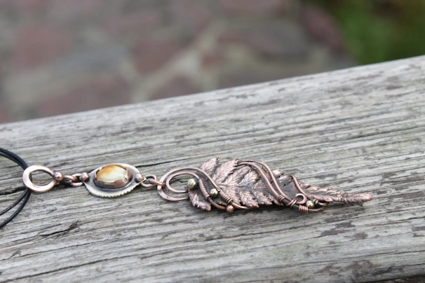 Handcrafted rose gold pendant necklace with intricate detailing, showcased on a natural stone slab.