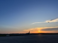 A scenic airport runway at sunset with a plane taking off, symbolizing new adventures.
