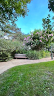 Peaceful garden area with stone benches and flowering plants under a clear blue sky